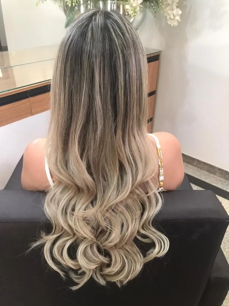 Cabelo loiro longo com mechas e ondas, visto de costas